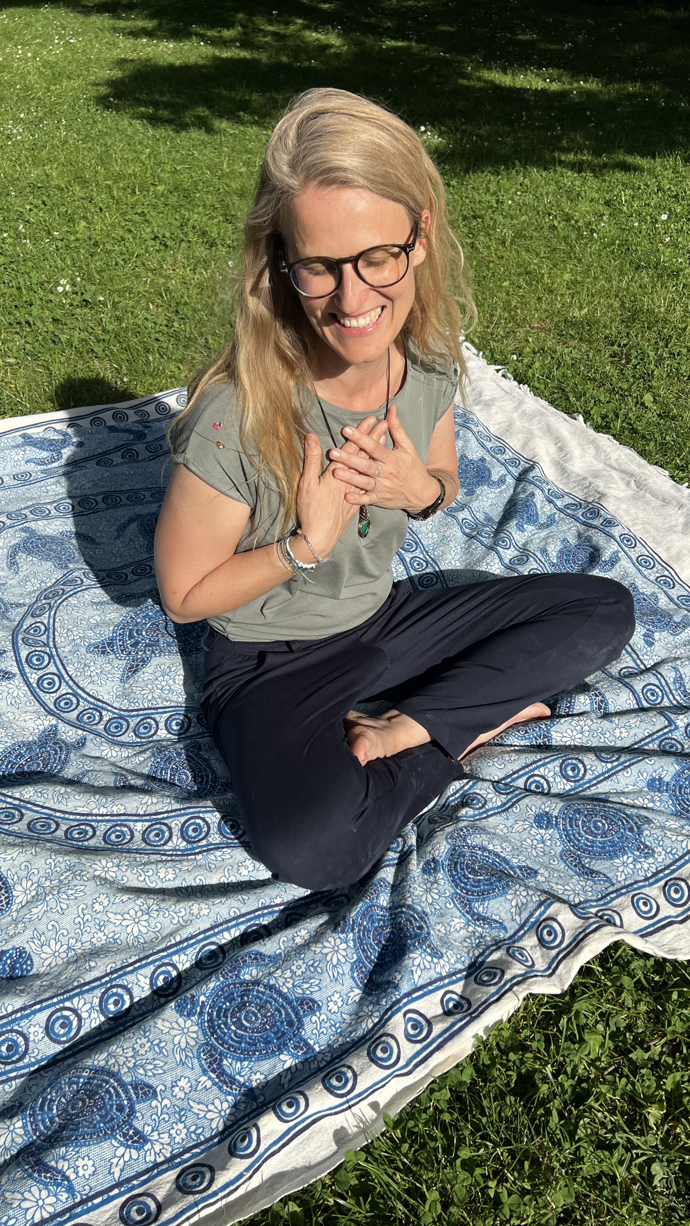 Petra Martinek, lächelnd im Schneidersitz im Freien